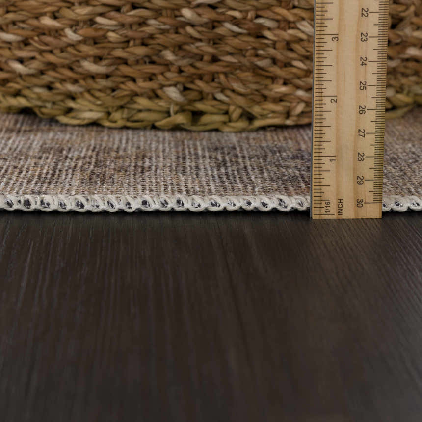 Close-up of the Carrabelle Peach Washable Area Rug showing the rug's edge, texture, and thickness with a ruler. Pile