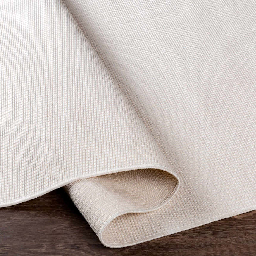 Close-up of the cream Currimundi Area Rug showing its woven texture and construction on dark wood flooring. Fold