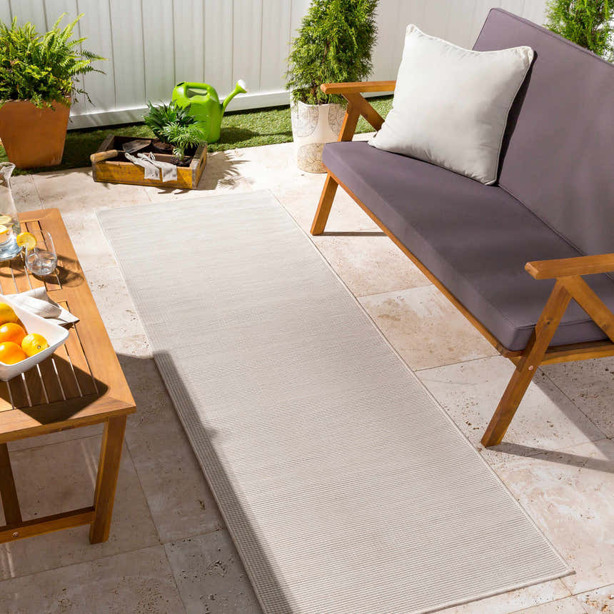 Outdoor patio scene with a cream Currimundi Area Rug runner, wooden furniture, and potted plants. Roomscene-Runner