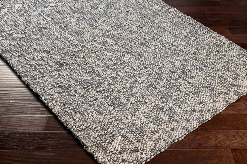 Close-up of the hand-loomed Cushendall Premium Rug. Dark blue and off-white contemporary design on wood floor. Corner