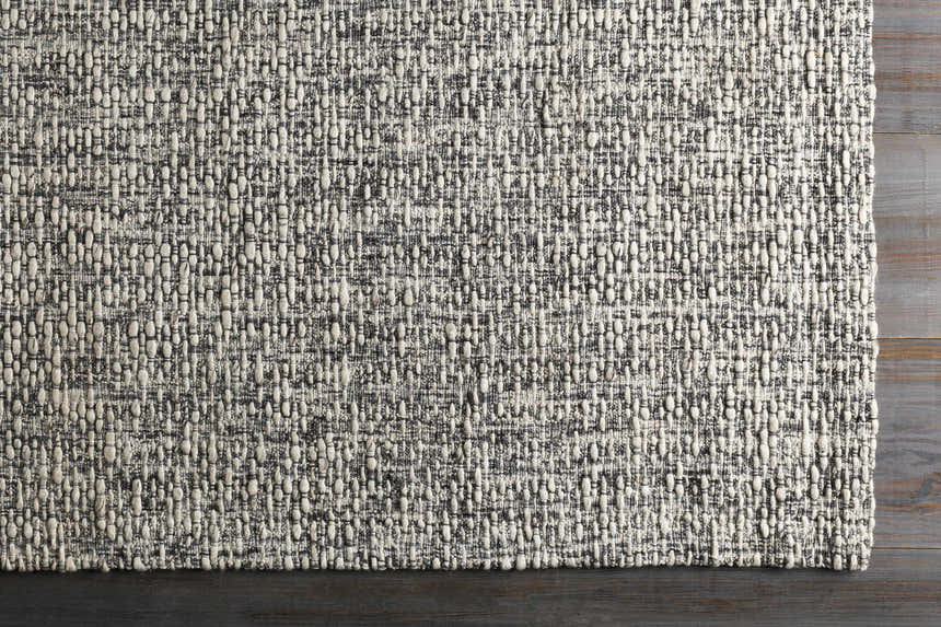 Close-up of the hand-loomed Cushendall Premium Rug. Dark blue and off-white yarns create a textured, contemporary design. Corner