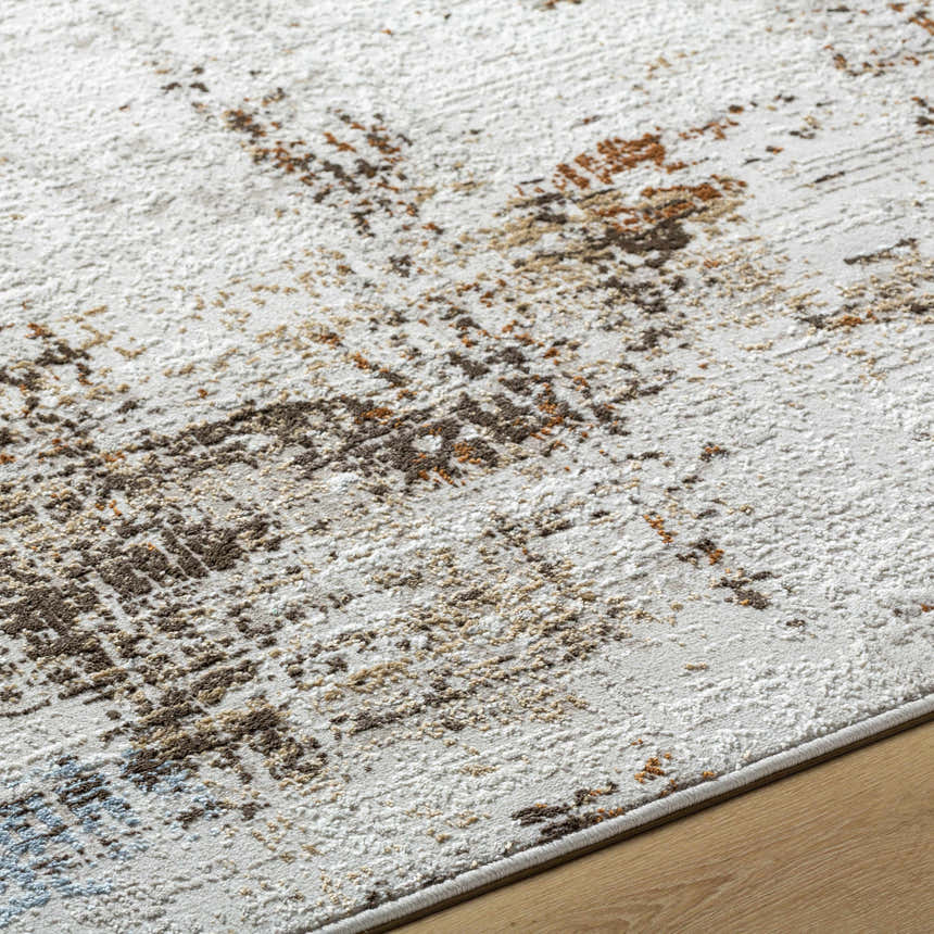 Close-up of the Utcha Area Rug. Abstract design in dark brown, denim, medium brown, mustard, taupe, and white. Polypropylene texture. Texture
