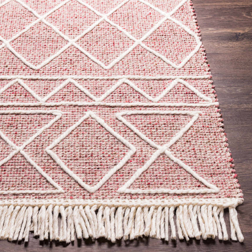 Close-up of the Dacudao Area Rug. Hand-woven wool rug in burgundy, cream, and dusty pink with geometric patterns and fringe. Front