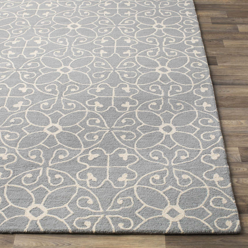 Close-up of the Davie Area Rug. Slate blue wool rug with an ivory floral pattern on a wood floor. Front