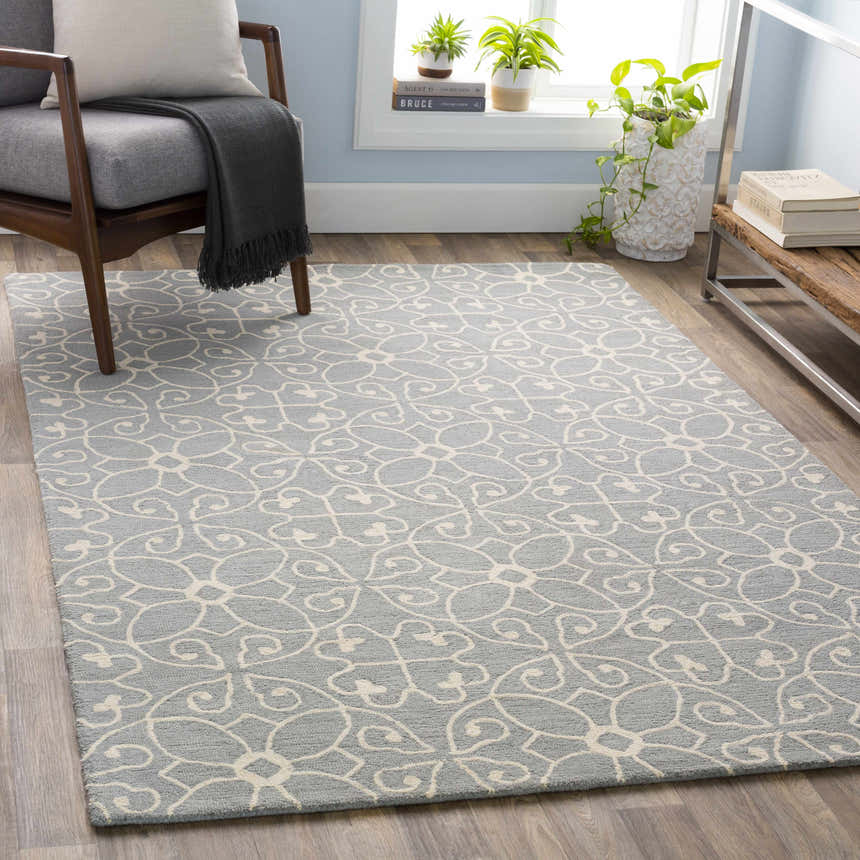 Living room scene with slate blue Davie Area Rug, ivory floral pattern, gray chair, and wood accents. Roomscene-Rectangle