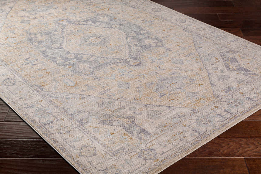 Close-up of the Deena Thick Luxe Area Rug with a traditional design in brown, charcoal, and gray on dark wood floors. Corner