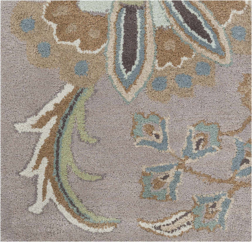 Close-up of the hand-tufted Denio Area Rug. Wool rug with brown, sage, taupe, and sky blue floral pattern on a light brown background. Swatch