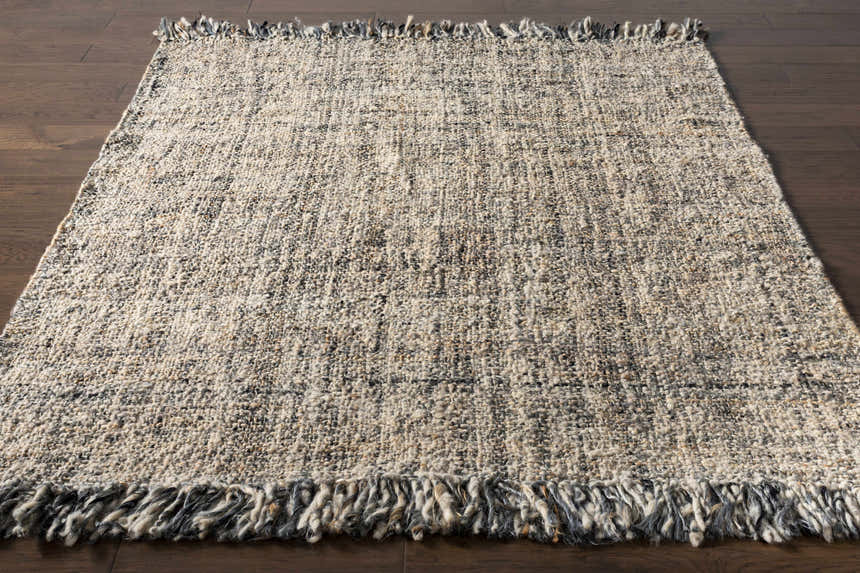 Hand woven Edgely Area Rug in black, gray, light beige, and tan wool and jute with fringe detail. Front