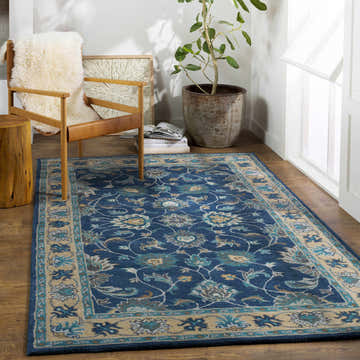 Living room scene with Cherryfield Hand Tufted Navy area rug, wood floors, chair with sheepskin, and potted plant. Roomscene-Rectangle