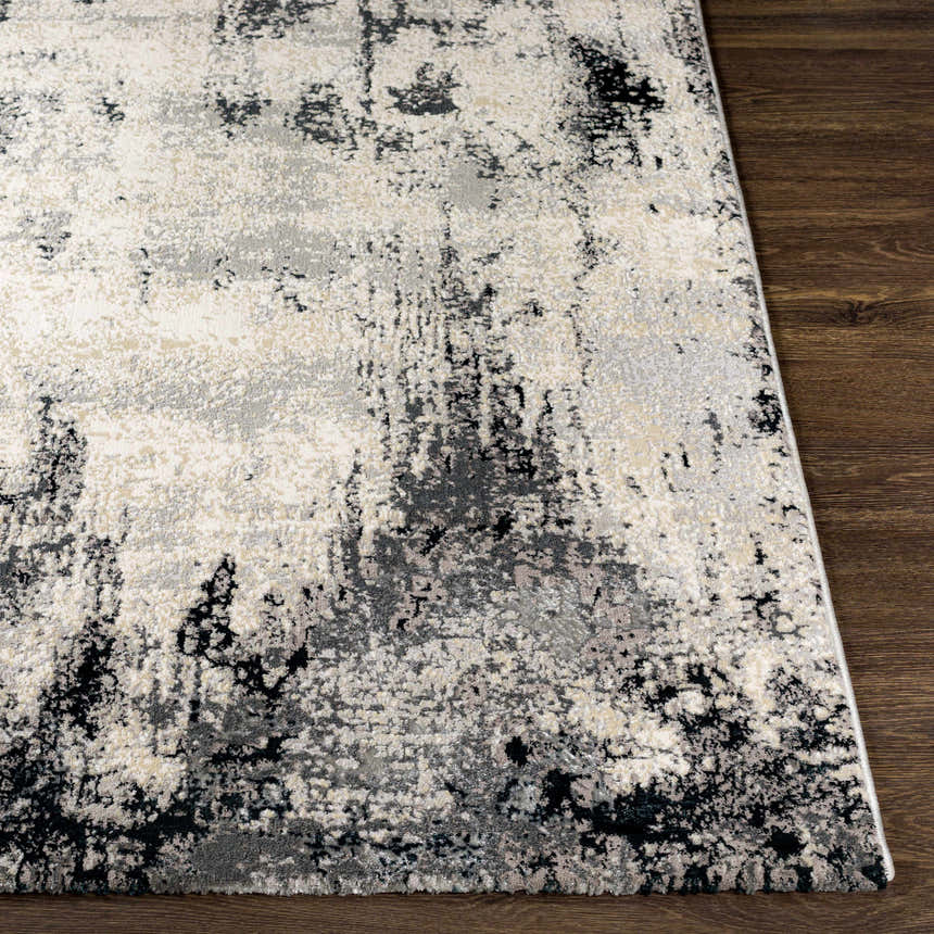 Close-up of the Dumangas Area Rug showing its abstract black, charcoal, cream, and gray pattern. Front