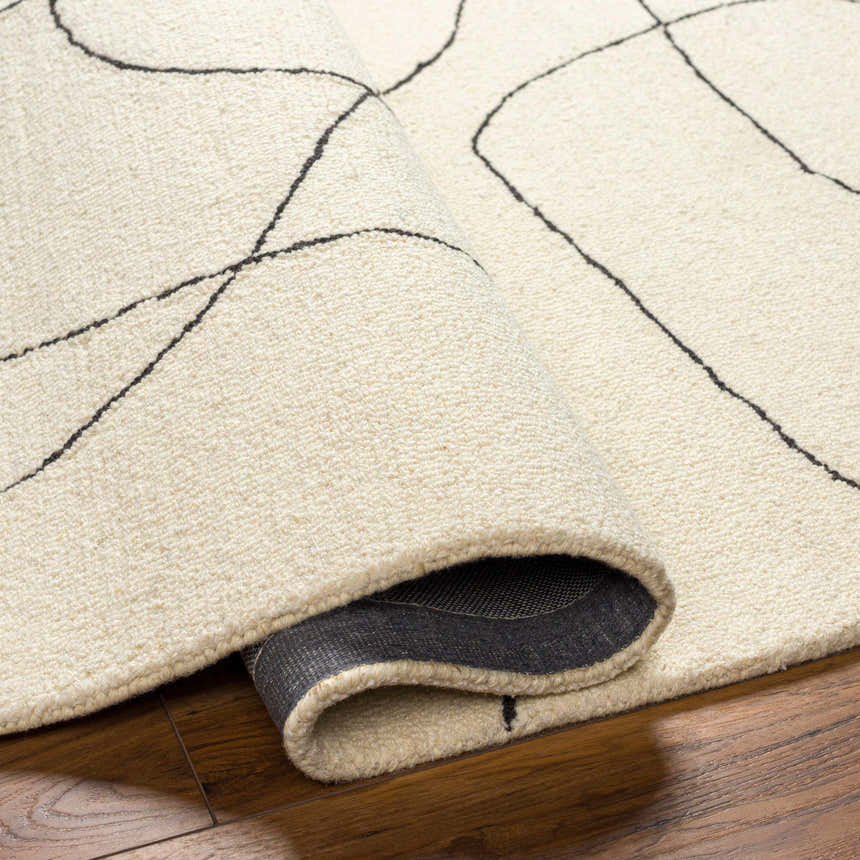 Close-up of the Deniz Modern Off-White Wool Rug, showing the texture and abstract gray line design. Rolled edge detail. Fold
