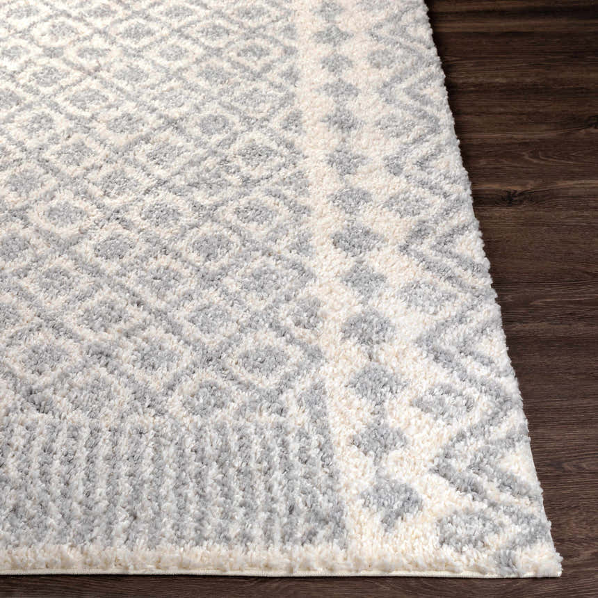 Close up of Downton Area Rug showing a geometric diamond pattern in gray and white on a dark wood floor. Front