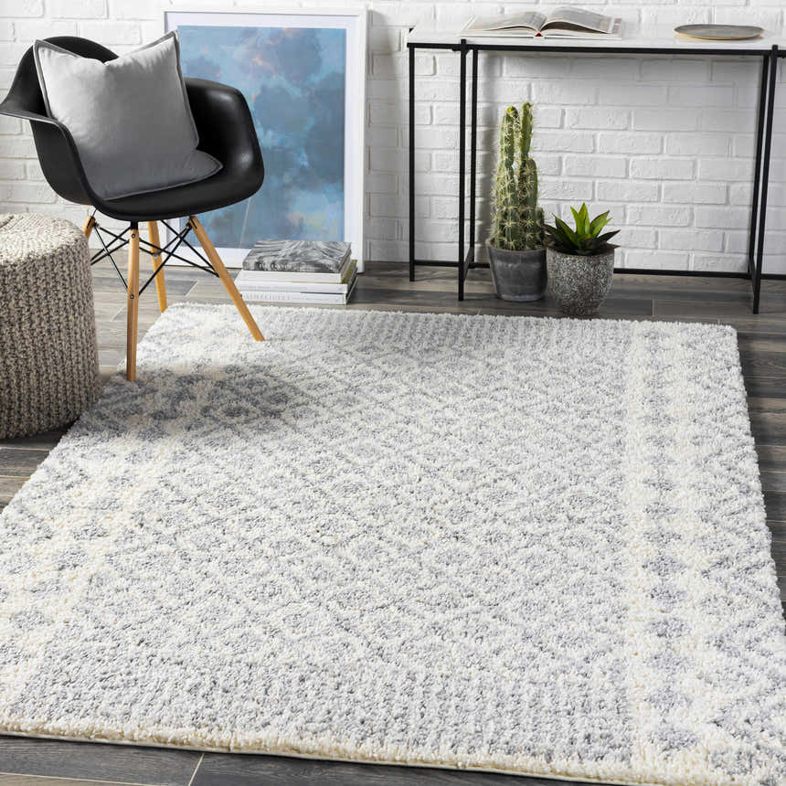 Modern room scene with a Downton Area Rug, black chair, gray pillow, and white brick wall. Roomscene-Rectangle
