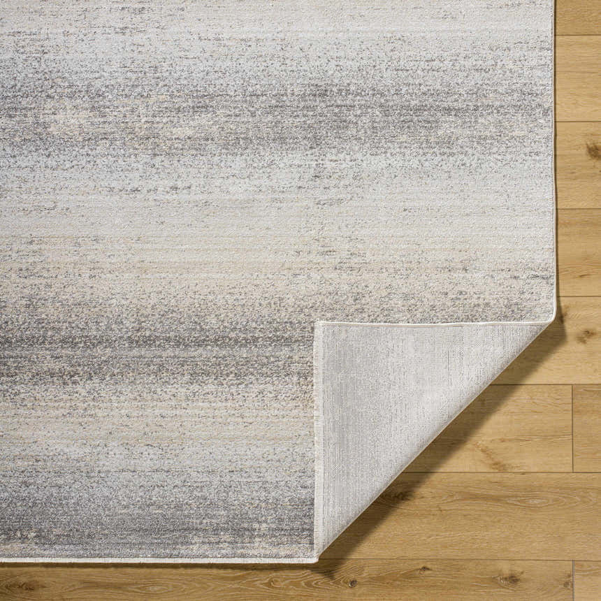 Close-up of Uzima Gray Area Rug showing light slate, medium gray colors and subtle contemporary pattern on wood floor. Fold