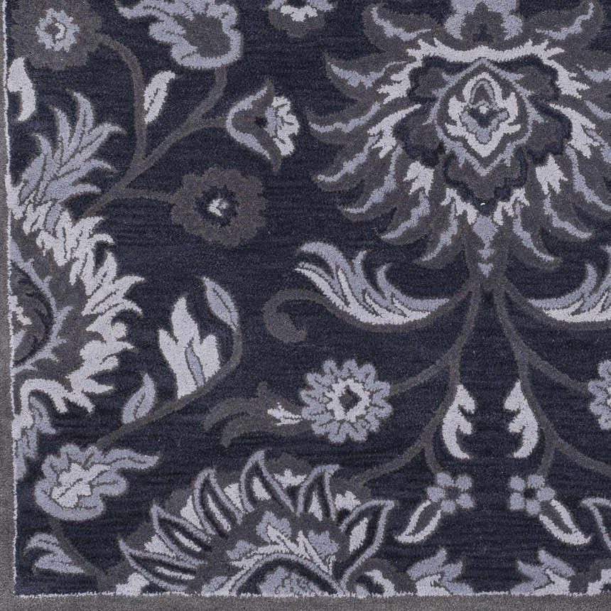 Close-up of the Conesus Hand Tufted Blue 1191 Area Rug. Features a traditional floral pattern in denim, charcoal, and slate blue. Swatch