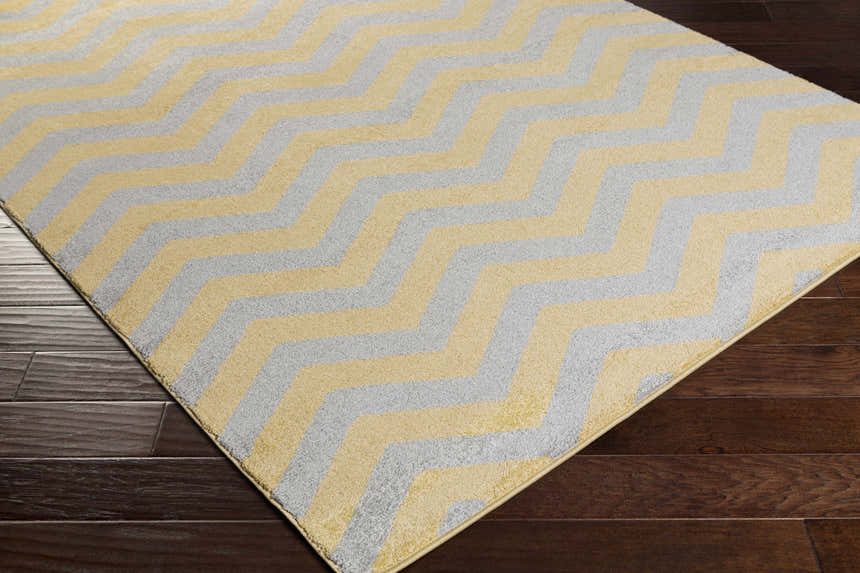 Close-up of the Eloy Area Rug. Charcoal and mustard chevron pattern on a soft, machine-woven polypropylene rug. Corner