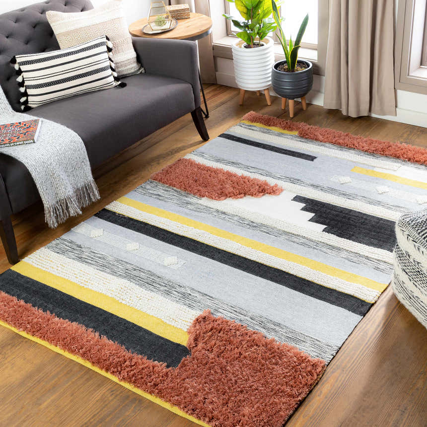 Living room scene with the Elsenham Area Rug: black, brick red, cream, gray, and mustard stripes. Bohemian style. Roomscene-Rectangle