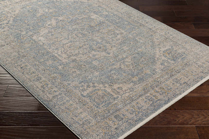 Close-up of the Tusa Blue Area Rug showing the traditional pattern and colors on a dark wood floor. Corner