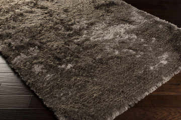 Close-up of the medium gray Erial Area Carpet, a hand-woven shag rug with a soft, textured pile on dark wood flooring. Corner