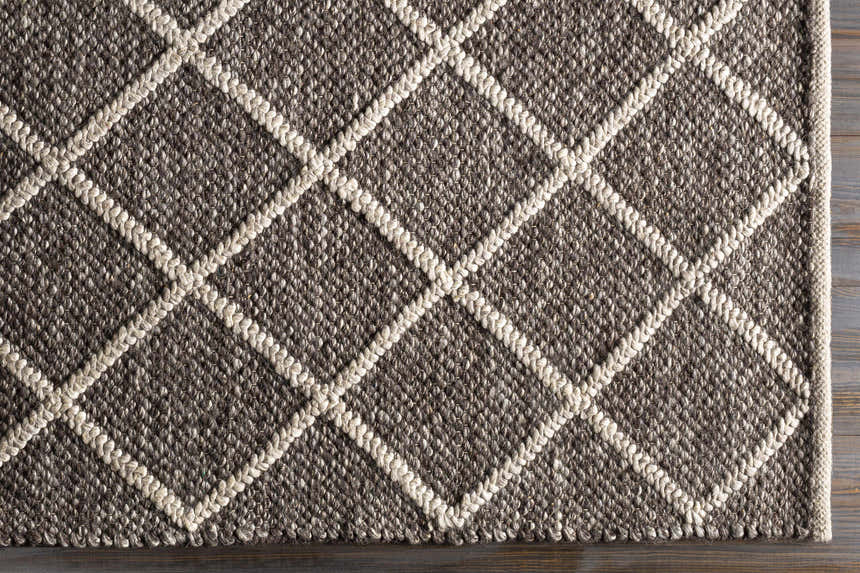 Close-up of the hand woven Syosset 2x3 Brown Trellis Wool & Viscose Rug. Brown rug with a cream diamond pattern. Corner