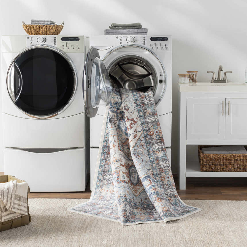 Laundry room scene with Eydie Washable Area Rug in blue, camel, and white coming out of a washing machine. Washing-Machine
