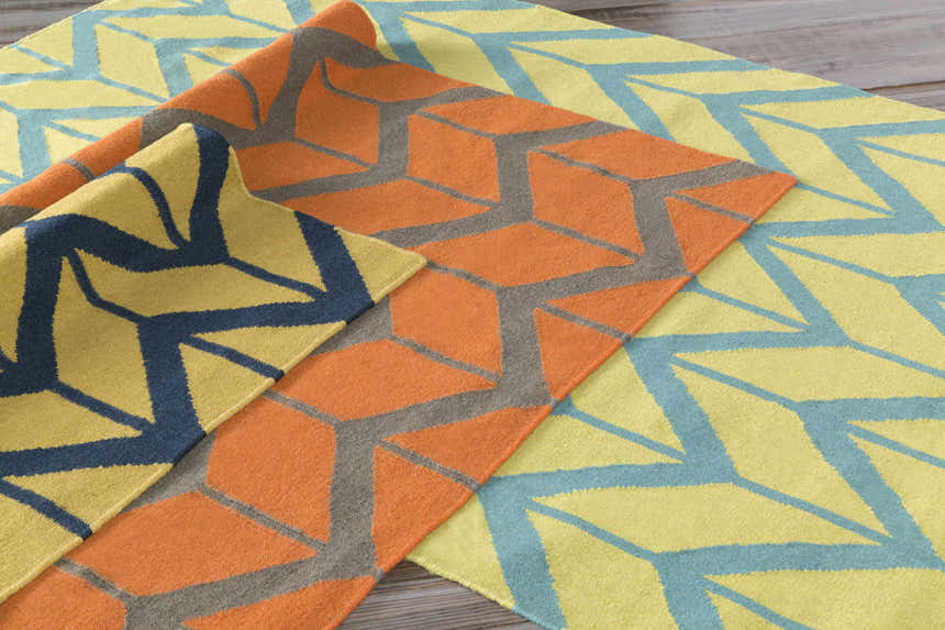 Close-up of the Eland Area Carpet showing its geometric pattern in dark blue, olive, and orange wool. Styleshot