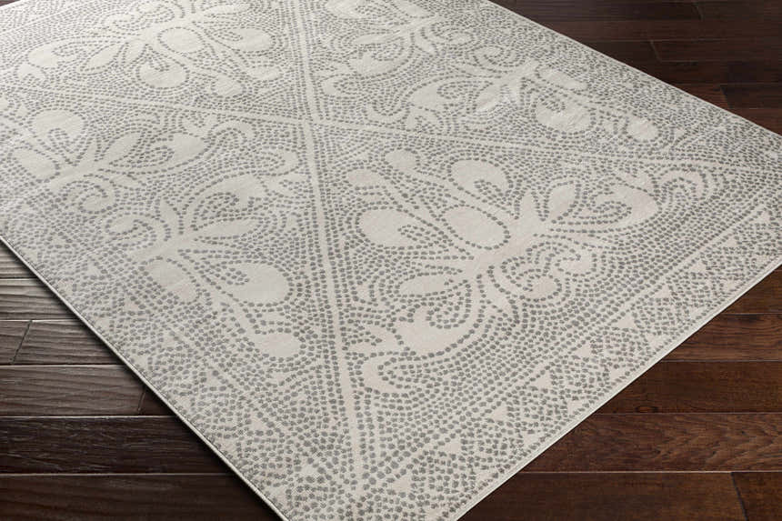 Close-up of Fernwood Area Rug with gray floral medallion pattern on a light gray background. Corner