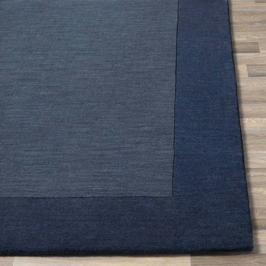 Close-up of a Bordered Solid Ink Blue Wool Rug showing the texture and color variation. Front