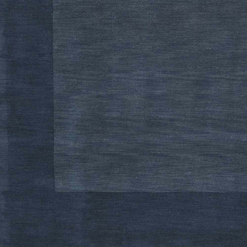 Close-up of the Bordered Solid Ink Blue Wool Rug showing its subtle texture and color variations. Swatch