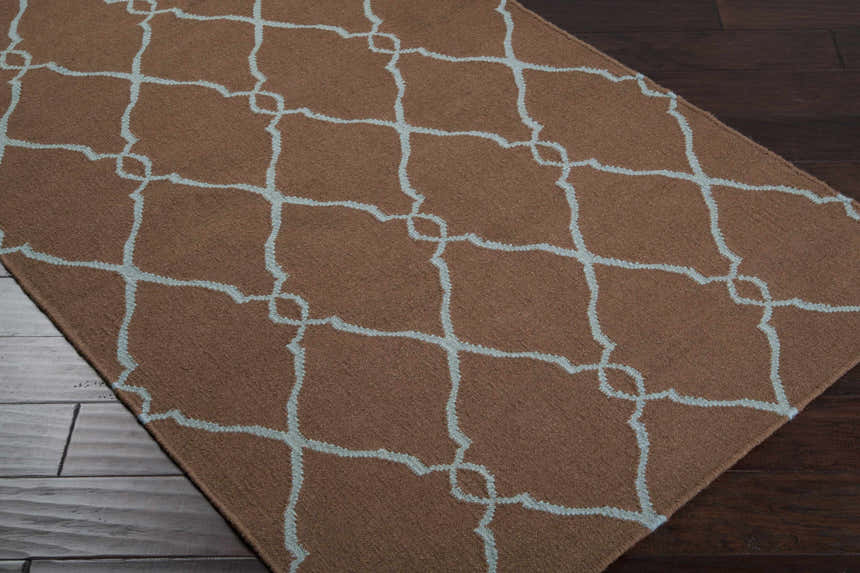 Close-up of the Frost Area Rug, a brown wool rug with a dusty sage geometric trellis pattern. Corner