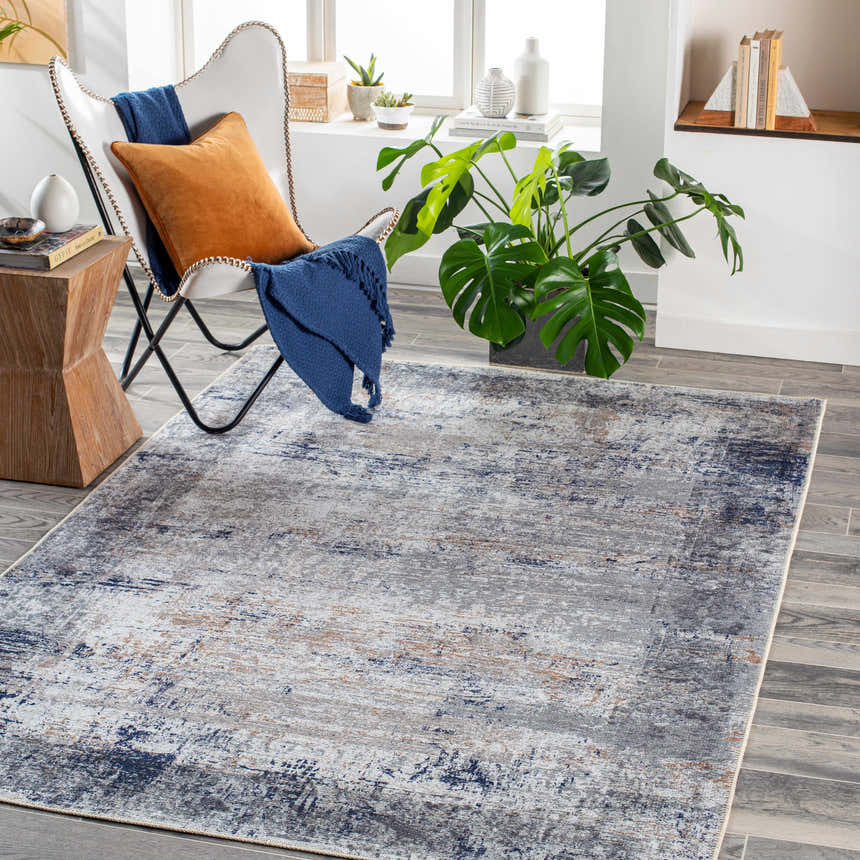 Living room scene with a Fairplains Washable Area Rug in charcoal, dark blue, and gray, styled with a butterfly chair and monstera plant. Roomscene-Rectangle