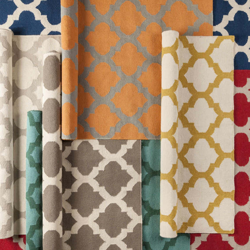 Close-up of rolled Banks Ivory/Gray Trellis Wool Rugs in various colors and trellis patterns. Styleshot