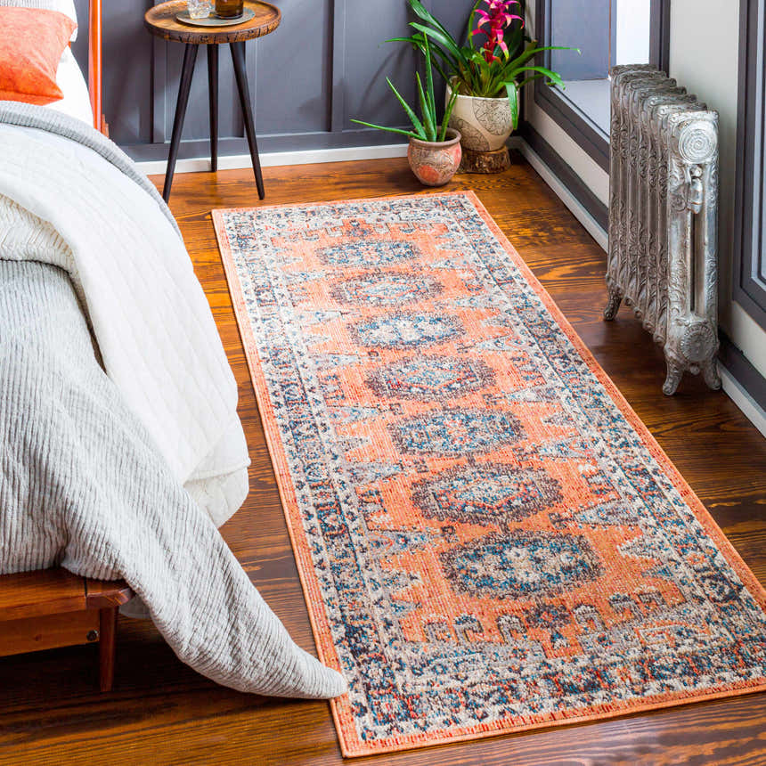 Bedroom scene with a Fullarton Performance Rug in brick red and blue, wooden floors, and a vintage radiator. Roomscene-Runner