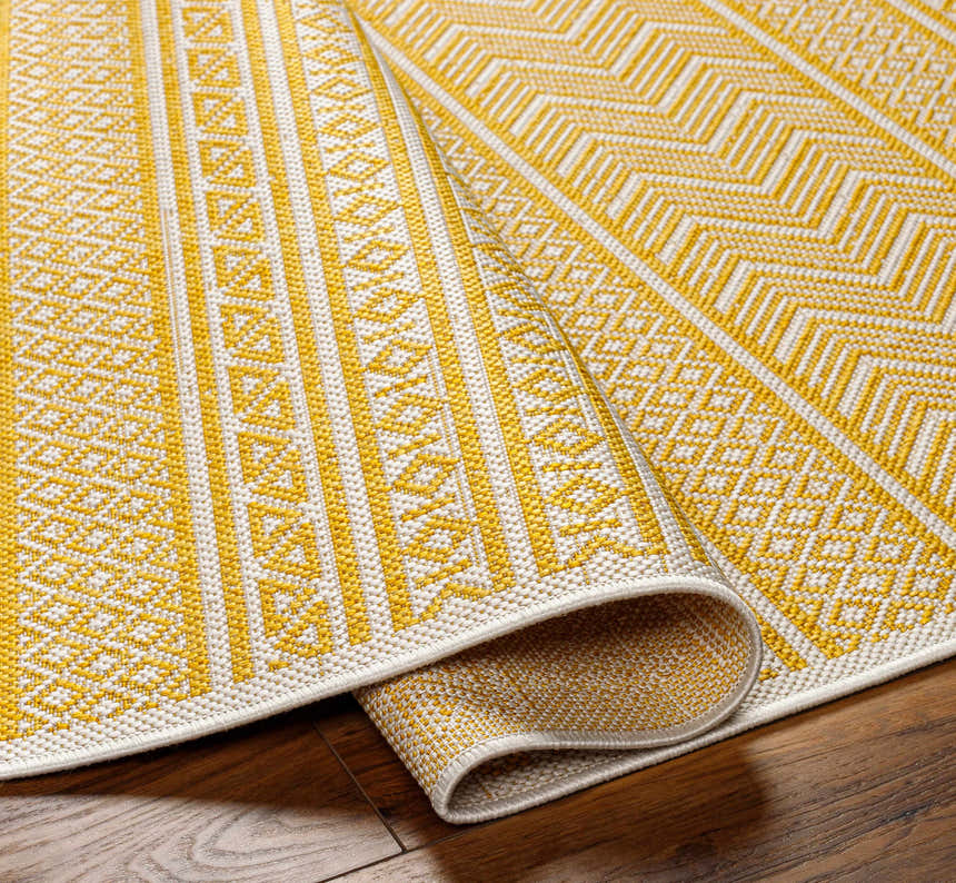 Close-up of the Galal Area Rug in beige and yellow. Farmhouse style rug with geometric pattern and machine woven texture. Fold