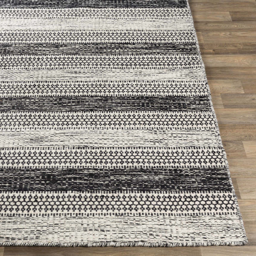 Close-up of hand woven Glengary Area Rug. Black and ivory rug with striped and geometric pattern on wood floor. Front