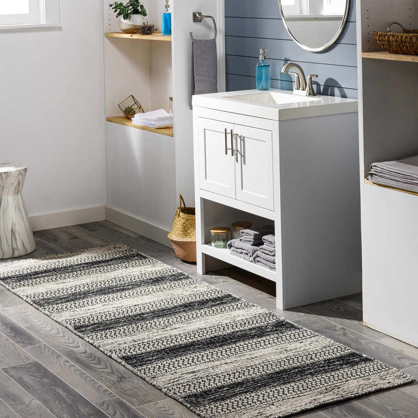 Bathroom scene with a black and ivory striped Glengary Area Rug on gray wood-look tile floor. Roomscene-Runner