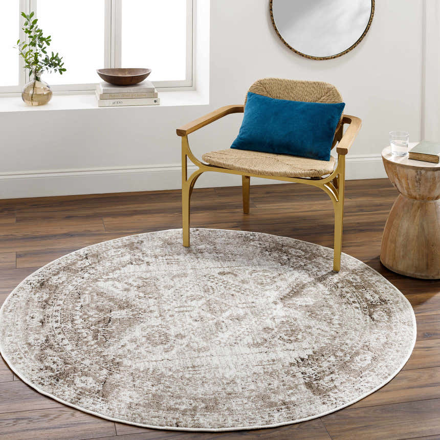 Living room scene with a round Gali Area Rug in cream and brown tones, styled with a chair and side table. Roomscene-Round