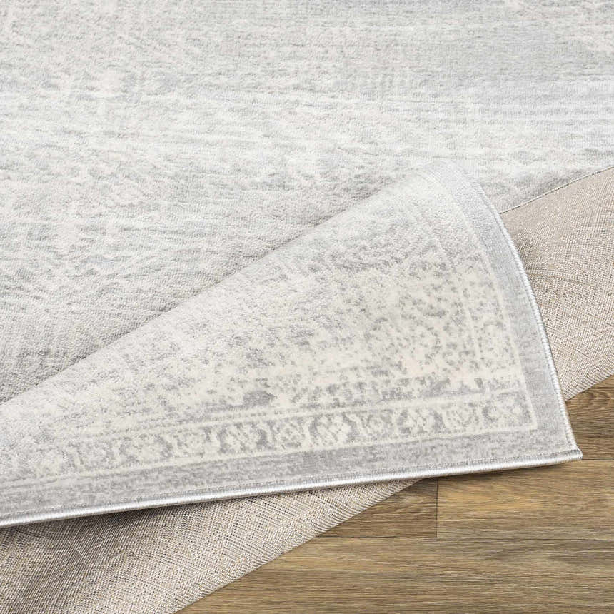 Close-up of the Gormania Area Rug showing its charcoal, light gray, and off-white bohemian pattern and machine-woven texture. Fold