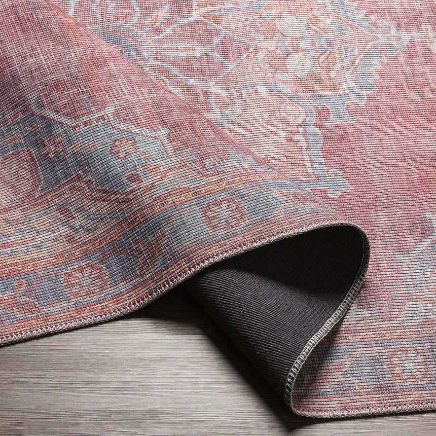 Close-up of the Goulburn Washable Area Rug, showcasing its traditional floral pattern in blue, burgundy, and beige tones. Fold