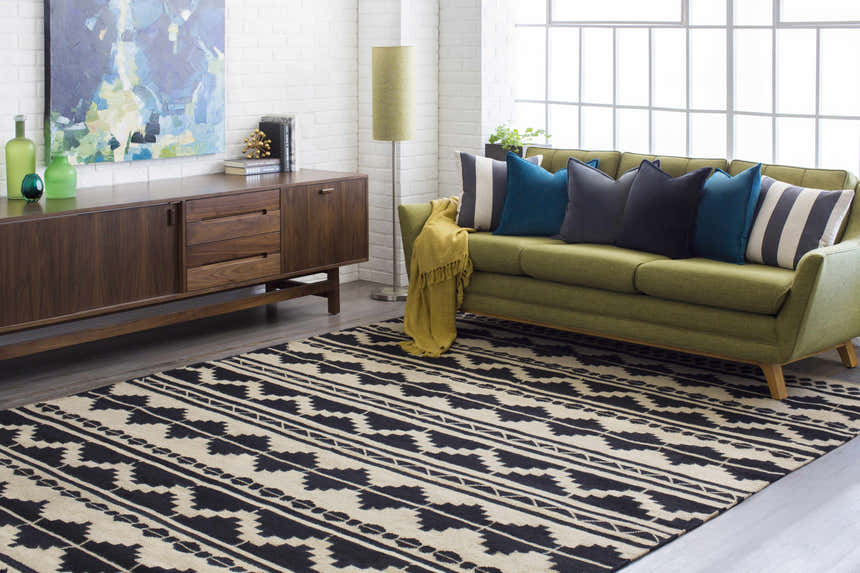Living room scene with a black and gray Gratiot Area Rug, green sofa, wood cabinet, and modern decor. Roomscene-Rectangle