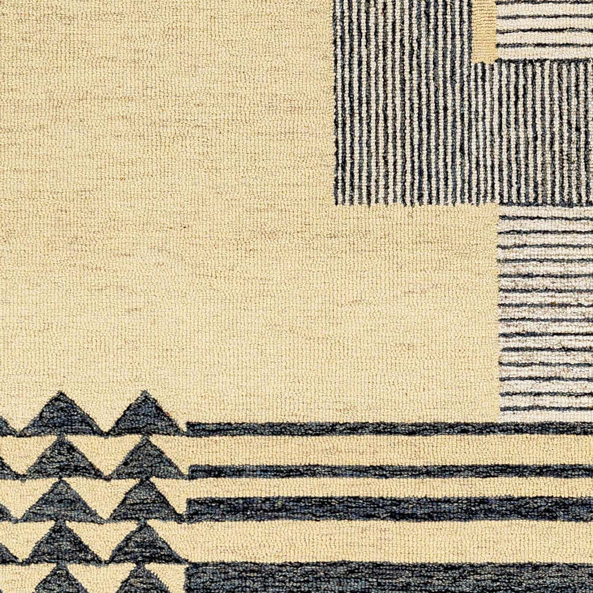 Close-up of the Guta Area Rug, a hand-tufted wool rug with beige background and black geometric triangle and stripe patterns. Swatch