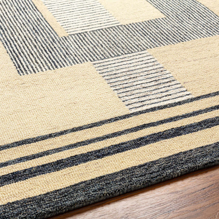 Close-up of the Guta Area Rug showing its beige and black geometric pattern and hand-tufted wool texture. Texture