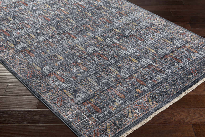 Close-up of the machine-woven Guirang Area Rug. Farmhouse style runner rug in shades of gray, rust, and gold on a wood floor. Corner