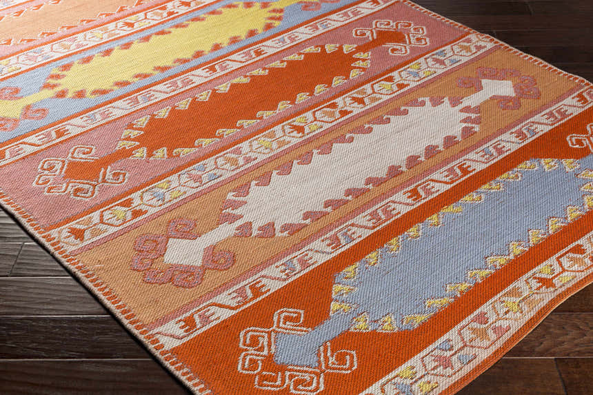 Close-up of Gumberry Area Rug showing brick red, denim, and mustard hues with a Southwestern-inspired geometric pattern. Corner