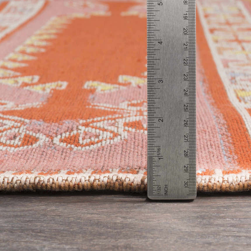 Close up of Gumberry Area Rug showing brick red, rose, and ivory pattern with a ruler for scale. Hand woven texture. Pile