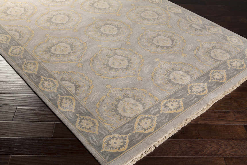 Close-up of the hand-knotted Haleiwa Clearance Rug. Camel and taupe floral medallions on a dark green wool rug. Corner