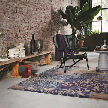Loft room scene with brick wall, Hallsboro Area Rug in charcoal, brown, gray tones, chair, and books. Roomscene-Rectangle