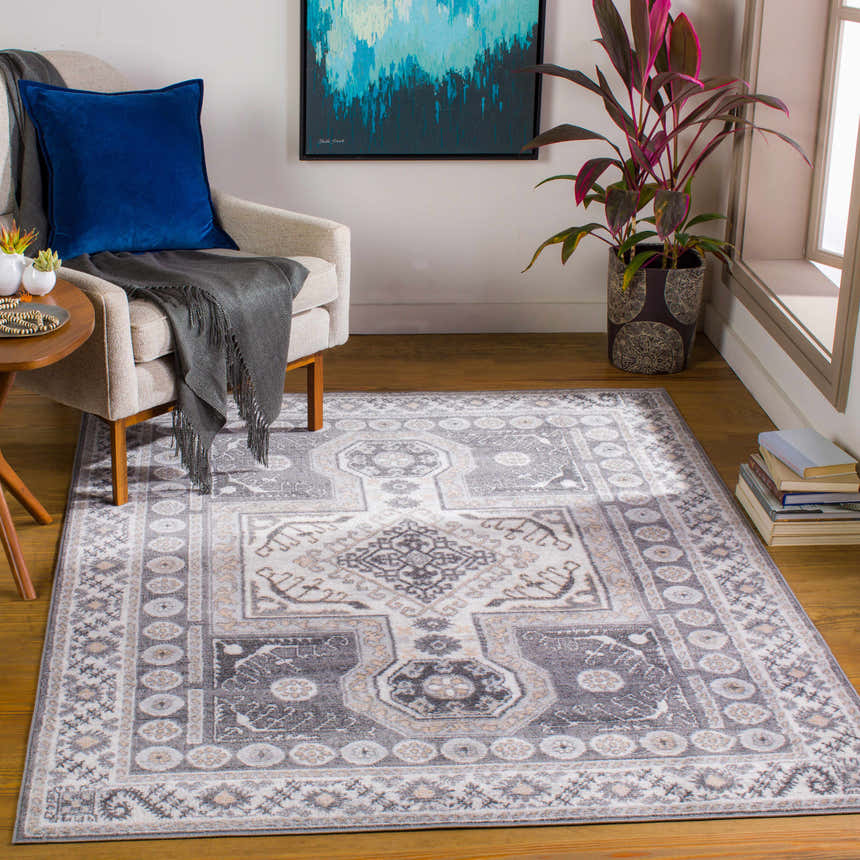 Living room scene with a Harrah Gray Cross Rug, beige armchair, blue pillow, and wood floors. Roomscene-Rectangle