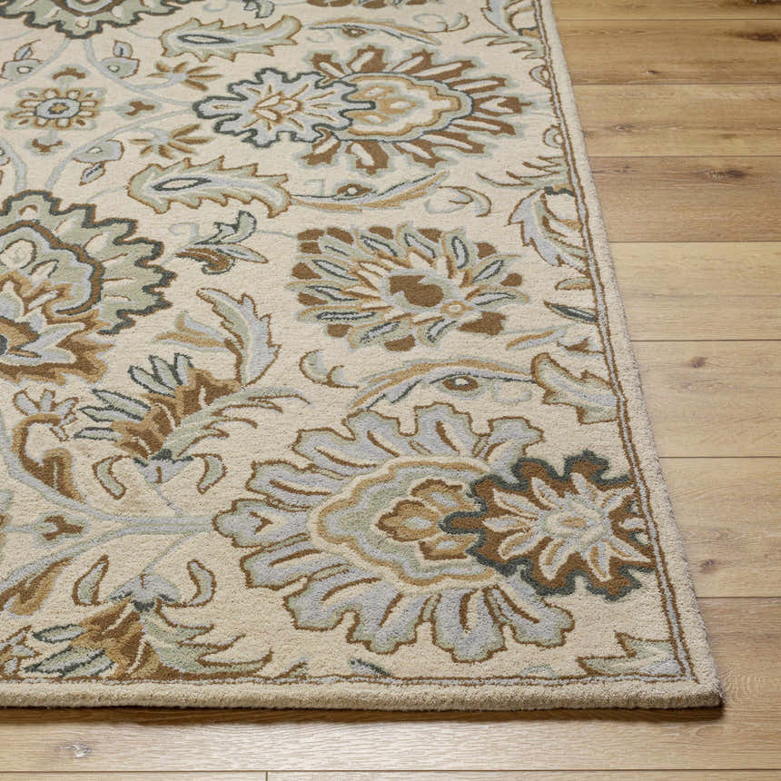 Close-up of the Helia Area Rug. Beige wool rug with a traditional floral pattern in brown, camel, and gray on wood floors. Front