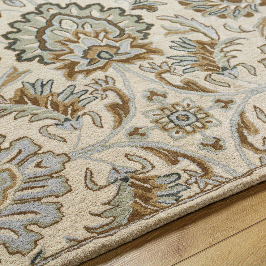 Close-up of the Helia Area Rug. Beige wool rug with a traditional floral pattern in brown, gray, and green tones. Hand-tufted texture. Texture